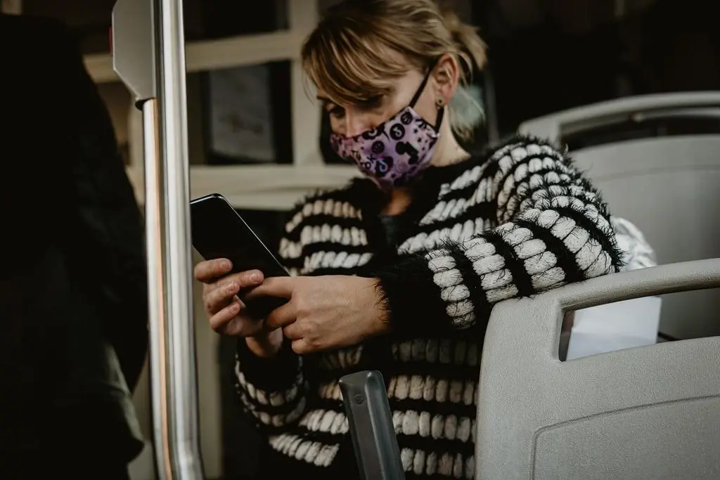 Una joven utilizando una masacrilla de tela en un autobús urbano