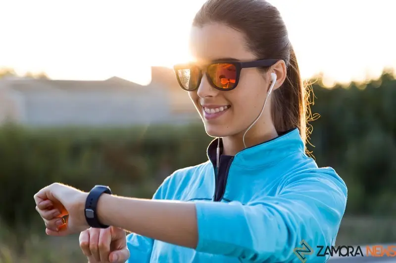 Outdoor portrait of young woman using they smartwatch after running.