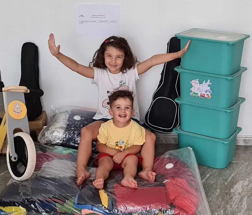 Los pequeños Helena y Miguel sobre algunas de sus pertenencias empaquetadas