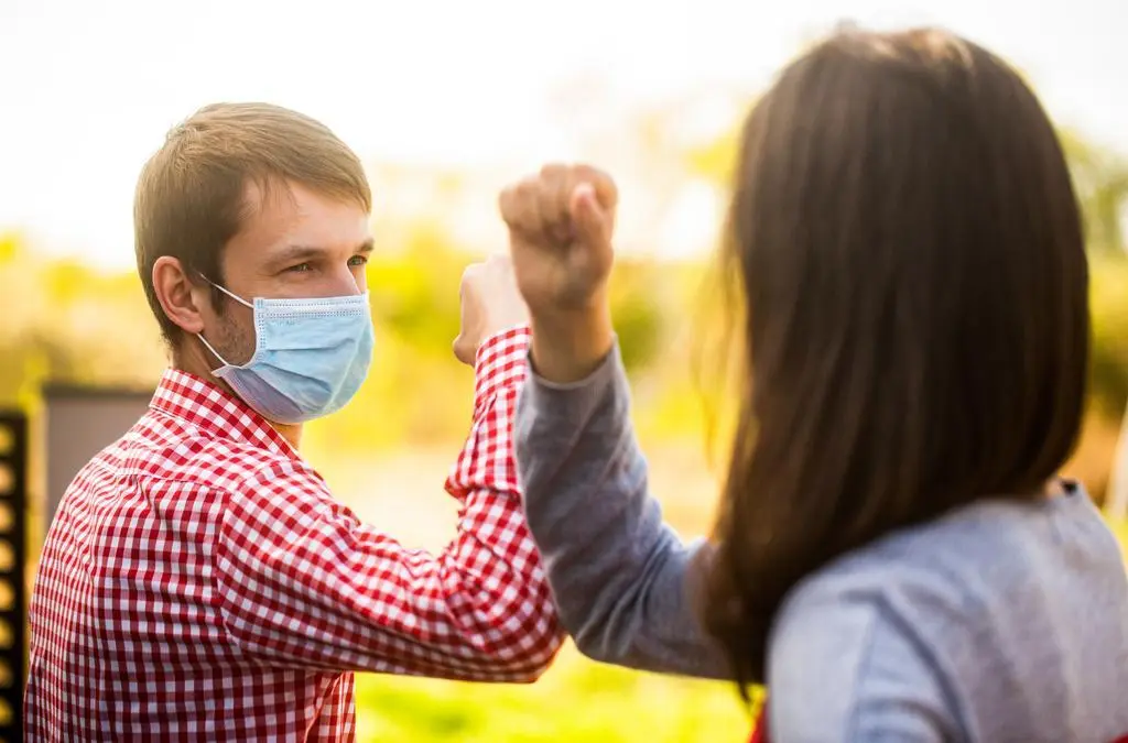 Friends in protective medical mask on his face greet their elbows in quarantine. Elbow bump. Coronavirus, illness, quarantine, medical mask, COVID19. Couple greeting with elbows. Elbows bump.
