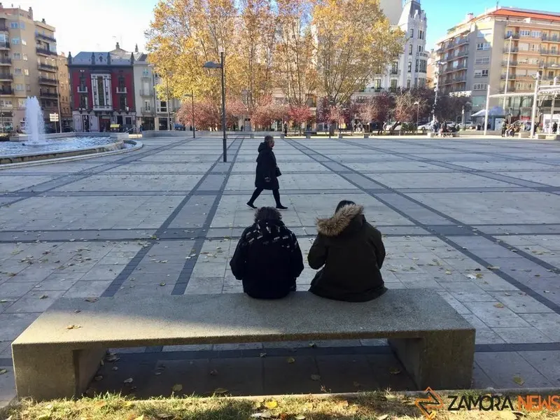 Dos personas descansan en un banco de la Plaza de la Marina