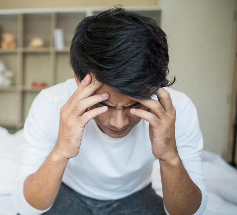 Upset man having problem sitting on the bed after arguing with his girlfriend
