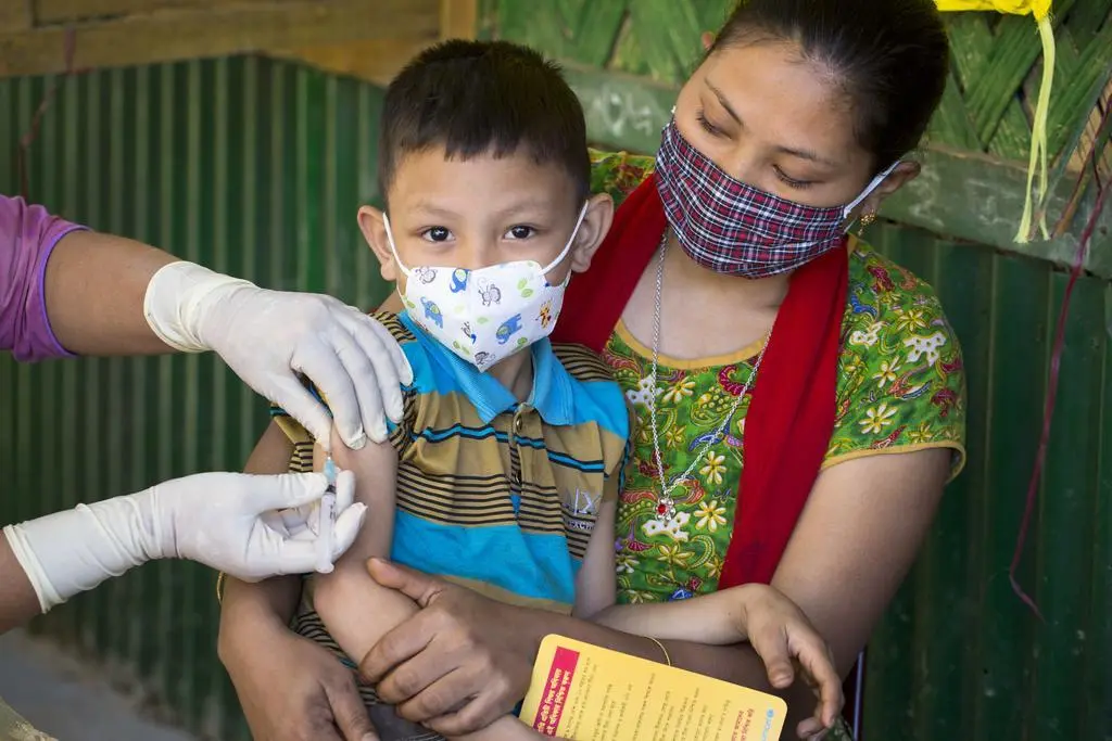 Tuhin Mara is sitting on his mother's lap, receives MR vaccine. Measles-Rubella (MR) Campaign 2020. Para Center, Hemonto Para. Betbunia Union, Kawkhali Upazila. 28 December, 2020
In an attempt to eliminate Measles and Rubella (MR) by 2023, Bangladesh aims to (i) provide one dose of MR vaccine to all children of 9 months to under 10 years to rapidly reduce transmission of MR virus, and (ii) identify all left-outs and drop-outs and reason for non-vaccination among children under 2 years for follow up vaccination. UNICEF assists GoB nationwide, while deploying innovative approaches in hard to reach areas such as Hill Districts, Riverine Areas, Tea Garden etc.

