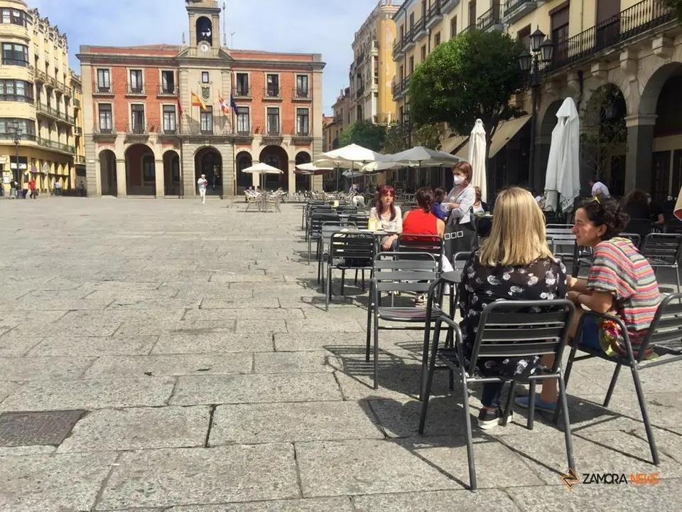 Varios paseantes disfrutando de la terraza en la Plaza Mayor