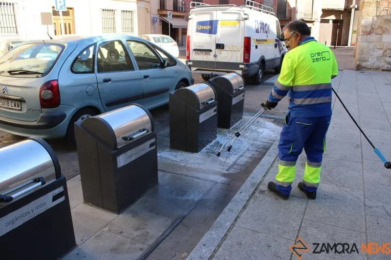 Un operario limpia pintadas cerca de los contenedores de basura