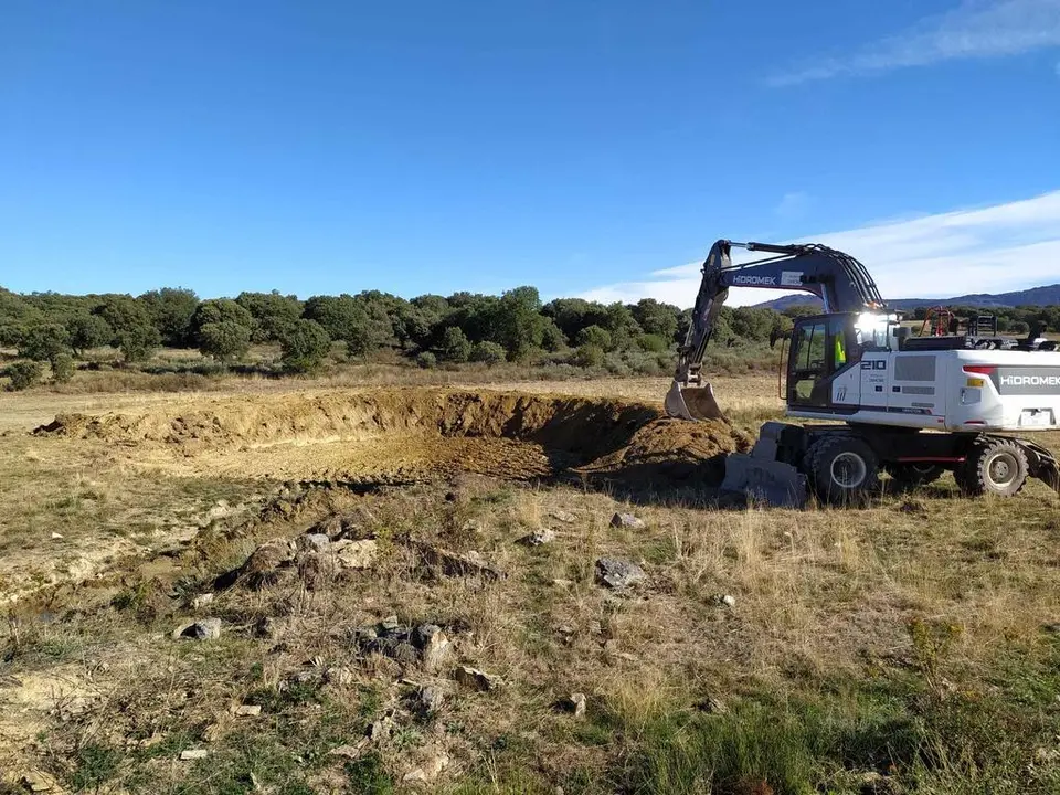 Una retroexcavadora trabaja para recuperar las balsas de agua ganaderas
