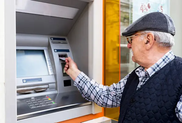 Pensionista sacando dinero de un cajero. Fotografía de archivo