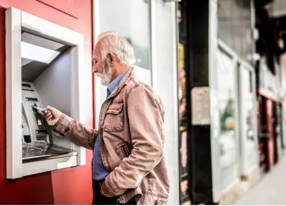 Pensionista sacando dinero de un cajero. Fotografía de archivo