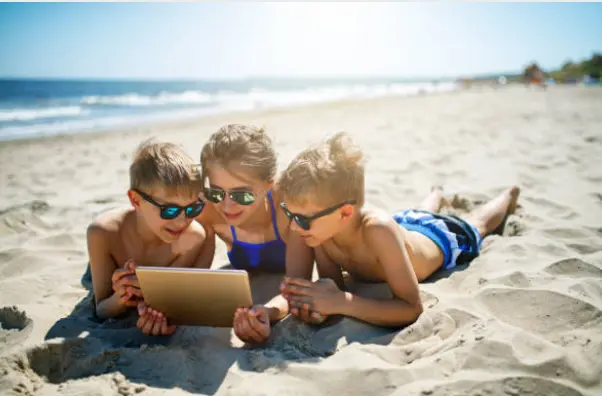 Niños utilizando una tableta en l aplaya. Fotografía de archivo