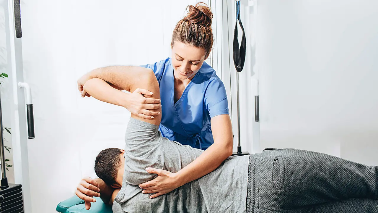 Physiotherapist treatment patient. She holding patient's hand, shoulder joint treatment