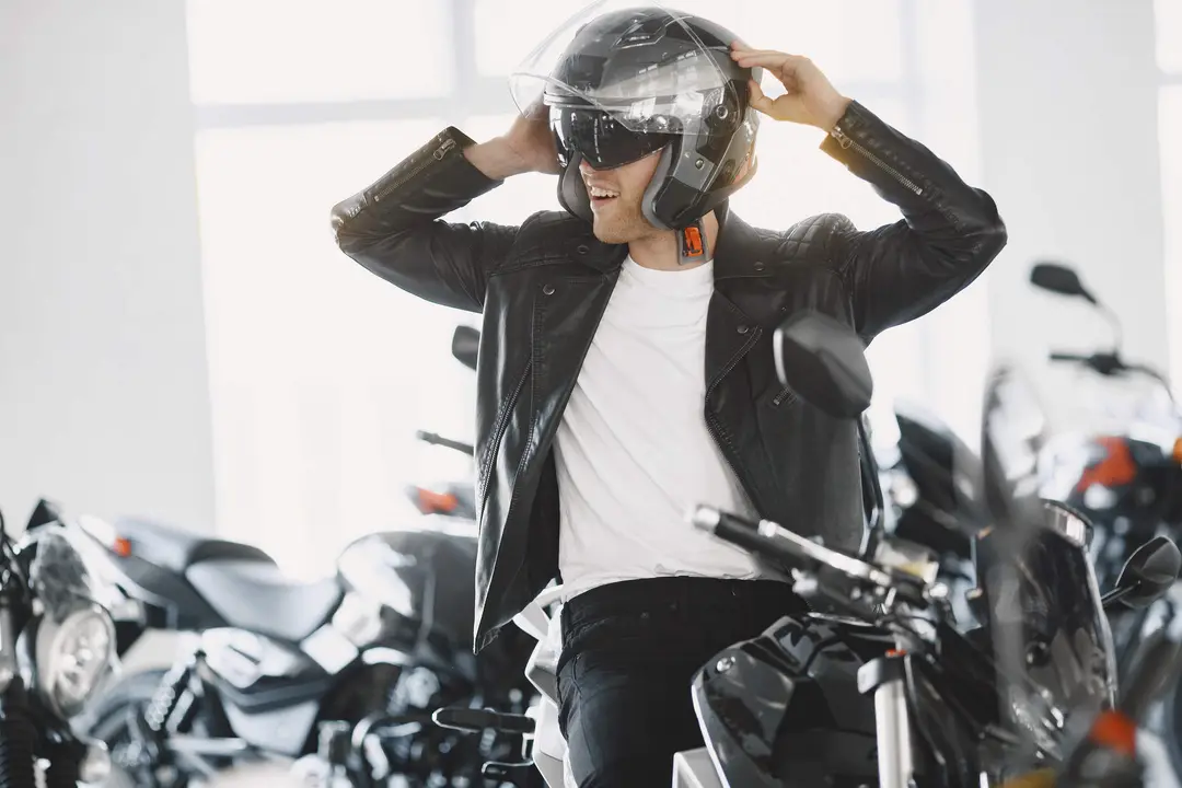 Man choosed motorcycles in moto shop. Guy in a black jacket. Man in a helmet.