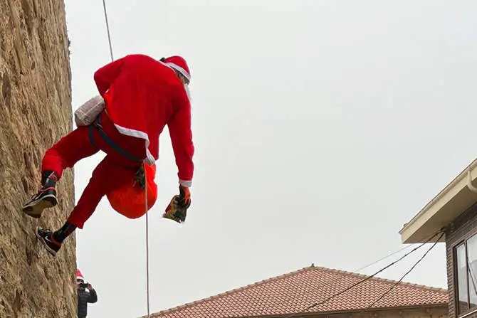 Papá Noel desciende por la pared de la iglesia de Maire de Castroponce