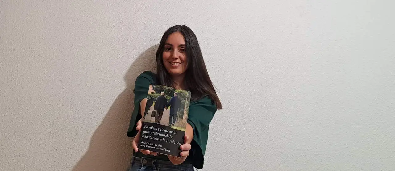Ana Calzón junto con su libro Familias y demencia Guía profesional de adaptación a la residencia
