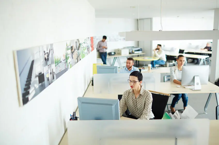 Contemporary businesswoman computing by her workplace in open space office