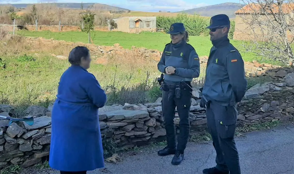 Pareja de la Guardia Civil conversa con una mujer mayor