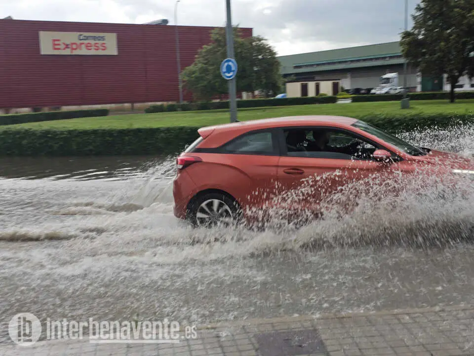 Coche circula por una calle anegada
