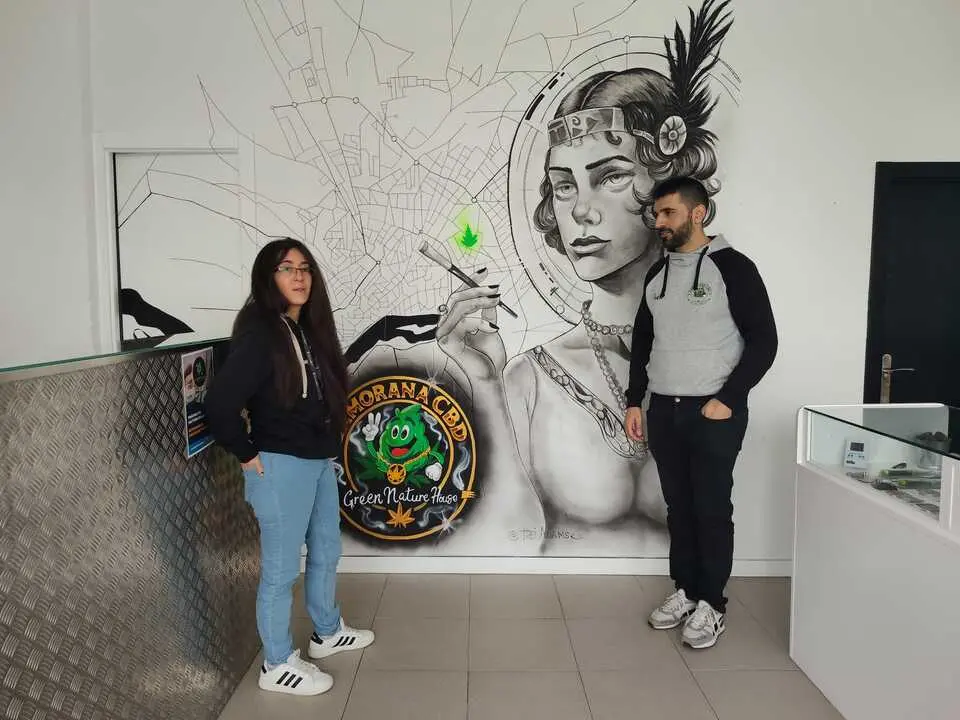 Pedro y Fany junto al mural que luce en la tienda de la Plaza de Cristo Rey