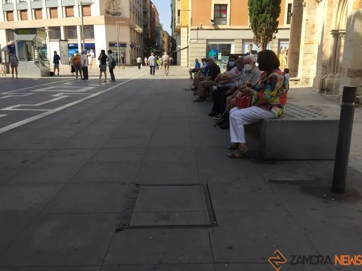 Gente sentada en los bancos de la calle Santa Clara