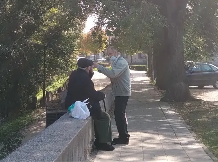 Dos personas mayores charlan en el entorno del puente de piedra