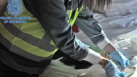 Una policía muestra parte del dinero incautado al grupo criminal