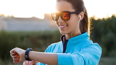 Outdoor portrait of young woman using they smartwatch after running.