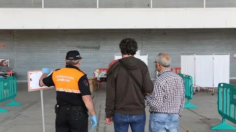 Protección Civil orienta a unos ciudadanos en el vacunódromo de IFEZA