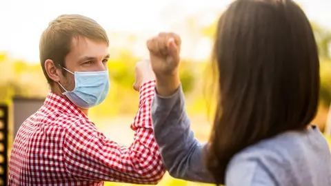 Friends in protective medical mask on his face greet their elbows in quarantine. Elbow bump. Coronavirus, illness, quarantine, medical mask, COVID19. Couple greeting with elbows. Elbows bump.