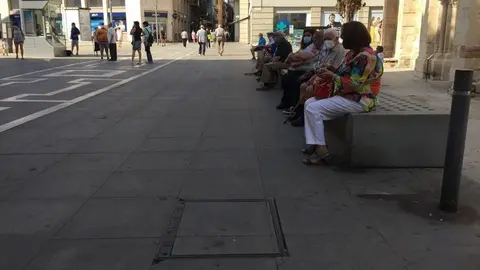 Gente sentada en los bancos de la calle Santa Clara