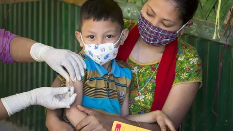 Tuhin Mara is sitting on his mother's lap, receives MR vaccine. Measles-Rubella (MR) Campaign 2020. Para Center, Hemonto Para. Betbunia Union, Kawkhali Upazila. 28 December, 2020
In an attempt to eliminate Measles and Rubella (MR) by 2023, Bangladesh aims to (i) provide one dose of MR vaccine to all children of 9 months to under 10 years to rapidly reduce transmission of MR virus, and (ii) identify all left-outs and drop-outs and reason for non-vaccination among children under 2 years for follow up vaccination. UNICEF assists GoB nationwide, while deploying innovative approaches in hard to reach areas such as Hill Districts, Riverine Areas, Tea Garden etc.

