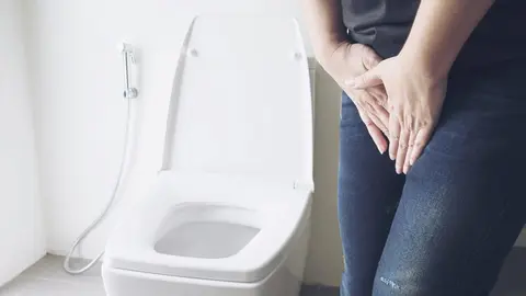 Woman holding hand near toilet bowl - health problem concept