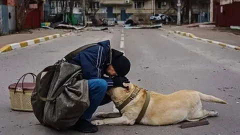 Hombre tranquiliza a un perro en Irpin