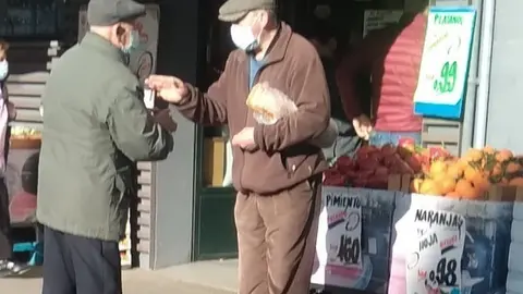 Dos personas mayores charlan frente a una frutería de Zamora