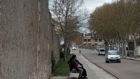 Dos personas conversan sentadas en un banco de Pinilla
