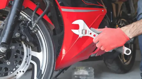 Mechanic using a wrench on a motorcycle. Garage. Work