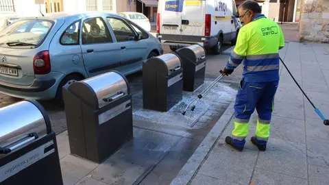 Un operario limpia pintadas cerca de los contenedores de basura