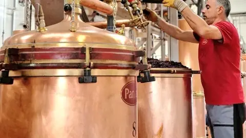 Operario cargando una caldera de orujo