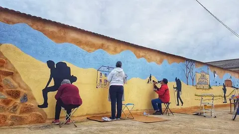 Los autores del mural pitando la pared