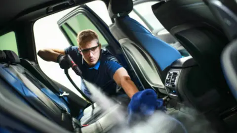 Trabajador en la limpieza de automoción. Fotografía de archivo