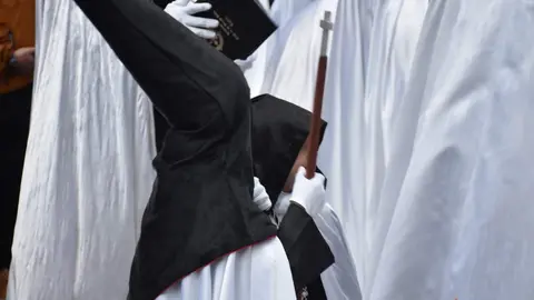 Cofrade con un bebé vestidos con la túnica de la Tercera Caída