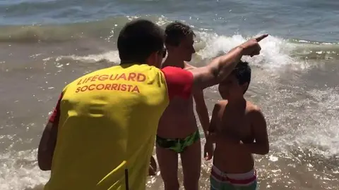 Un socorrista da consejos a una niños en una playa vía RFESS