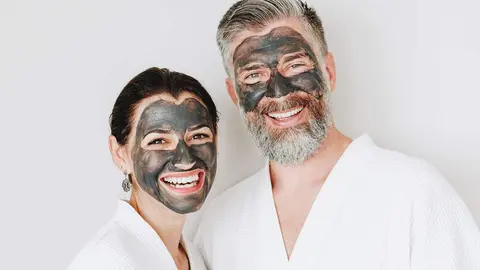 Happy couple wearing a charcoal mask