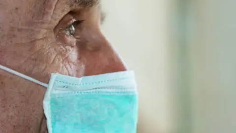 Persona mayor con mascarilla. Fotografía de archivo