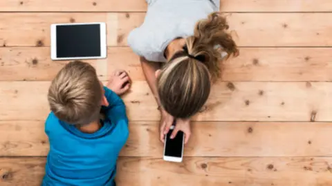 Fotografía de archivo de niños jugando con dispositivos electrónicos