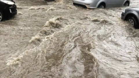 Coche circulando durante una inundación