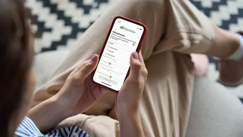 Young woman or teen girl hands holding mobile smart phone with mockup white blank display, empty screen at home. Shopping, delivery apps, social media applications ads, over shoulder close up view.
