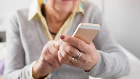 Persona de la tercera edad utilizando un dispositivo móvil. Fotografía de archivo