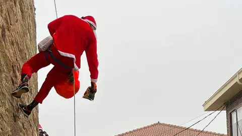 Papá Noel desciende por la pared de la iglesia de Maire de Castroponce