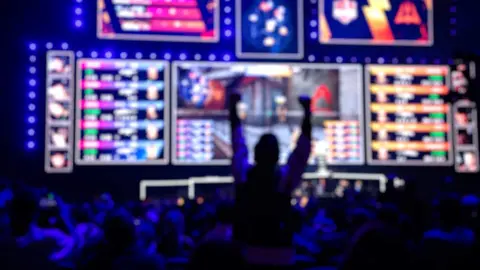 Blurred background of an esports event - Fan on a tribune at tournaments arena with hands raised.