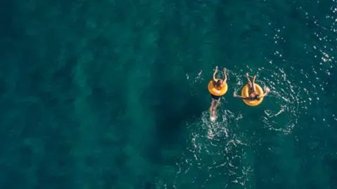 Bañistas con un rosco hinchable en el mar. Fotografía de archivo