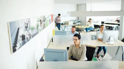 Contemporary businesswoman computing by her workplace in open space office